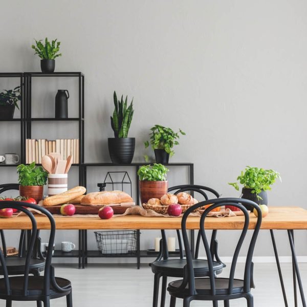 Sleek black dining chairs around a wooden table with fresh apples in a dining room