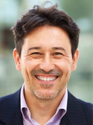 Confident older businessman in a suit smiling warmly at the camera